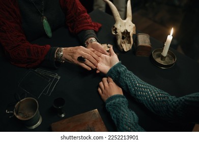 Top view fortune teller and client hands over table with spiritual attributes