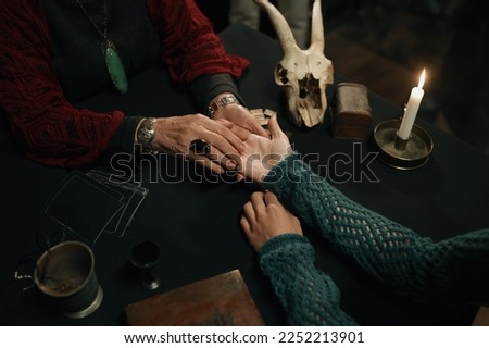 Top view fortune teller and client hands over table with spiritual attributes