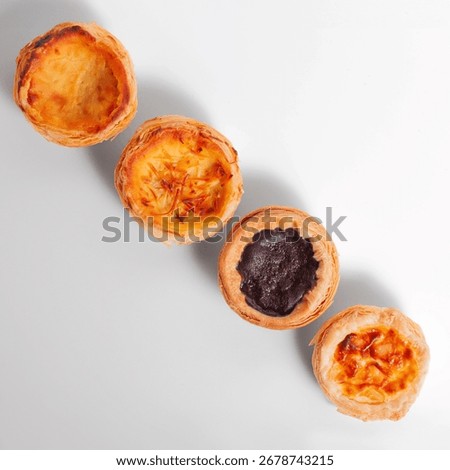 Top view of four assorted egg tarts with various fillings on white table