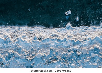 Top view of the freezing sea. Winter aerial photograph of the icy coast and ice floes in sea water. Nature of the Extreme North. Cold frosty winter weather. Harsh arctic climate. Natural background.