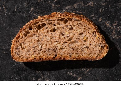 Top View Of Fresh Baked Whole Grain Bread Slice On Stone Black Surface