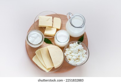 Top view of fresh dairy products: milk in a jug, cottage cheese, yogurt, sour cream and butter on a wooden round podium on a light background. Organic farm natural healthy food. Flat lay, close-up - Powered by Shutterstock