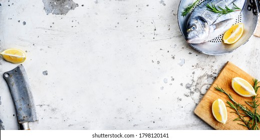 Top View Of Fresh Fish In Pan With Lemon And Rosemary On Rustic White Kitchen Table. Sea Food Dinner Preparation From Above. Luxury Restaurant Menu Design Banner With Seafood On Textured Backgrond.