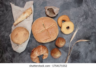 Top view of Fresh fragrant bread on dark board with wheat, banana cupcakes, croissant and donut. Bakery loaves of bread and buns.  Food concept. copy space. - Powered by Shutterstock