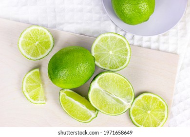 Top View Of Fresh Green Juicy Limes And Lime Slices In The Kitchen On Light Background