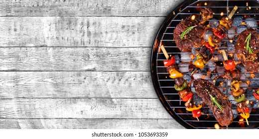 Top view of fresh meat and vegetable on grill placed on wooden floor. Barbecue, grill and food concept - Shutterstock ID 1053693359