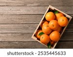 Top view of fresh oranges in wooden crate on wood planks.