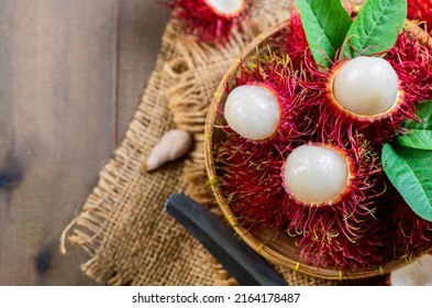 Top view of Fresh Rambutan fruits with leaves on bamboo basket isolated on wood background. fruit Southeast Asia,
