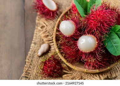 Top view of Fresh Rambutan fruits with leaves on bamboo basket on wood background. fruit Southeast Asia,