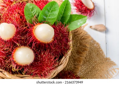 Top view of Fresh Rambutan fruits with leaves on bamboo basket on wood background. fruit Southeast Asia in summer season