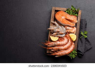 A top view of fresh seafood such as shrimp, langoustines, and trout steaks in wooden box. Flat lay with copy space