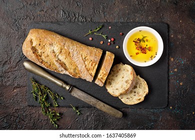 Top view of fresh wholegrain bread with olive oil in white bowl and thyme spice on black slate board and dark grunge background
 - Powered by Shutterstock