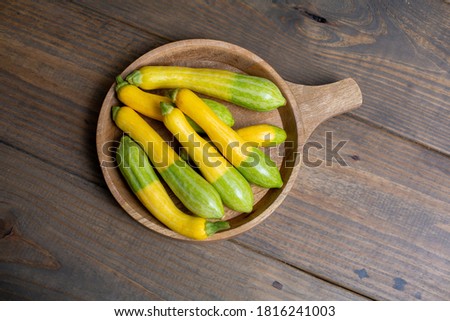 Top View of Fresh Zephyr Squash in a Wooden Bowl on a Wooden Table