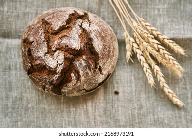 Top view of freshly baked rye bread on a yeast-free starter and on a mixture of whole grain, rye and wheat flour. It lies on a napkin, next to a dried flower with grains. Selective focus.  - Shutterstock ID 2168973191