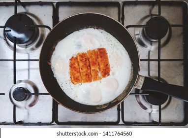 Top View Of Fried Eggs And Fish Fingers In A Pan On A Steel Gas Stove