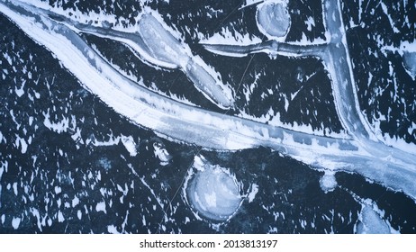 Top View Of A Frozen Pond With Thin Cracked Ice Covered With Ice Patterns. Copy Space.