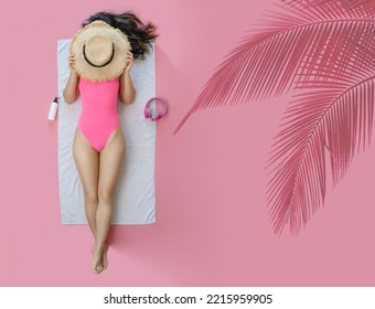 Top view full body young woman wearing pink swimsuit cover face with hat lies on white towel in pool isolated on plain pastel pink background. Summer vacation sea rest sun tan concept.