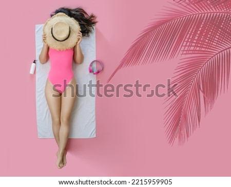 Top view full body young woman wearing pink swimsuit cover face with hat lies on white towel in pool isolated on plain pastel pink background. Summer vacation sea rest sun tan concept.