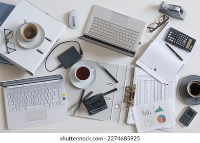 Top view of a full business desk with laptops, accounting papers, calculator, coffee and other office supplies, success work or stress concept, high angle shot from above, selected focus - Shutterstock ID 2274685925
