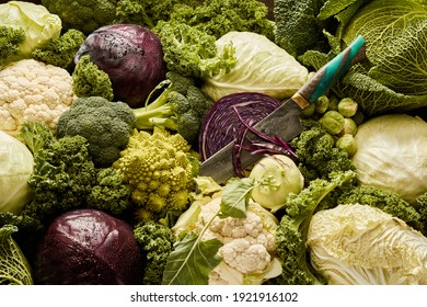 Top view of full frame background of various sorts of ripe cabbages and knife