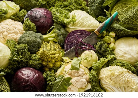 Top view of full frame background of various sorts of ripe cabbages and knife
