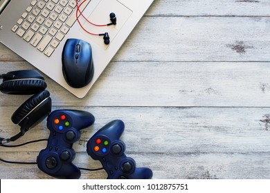 Top View Of Gamepads, Laptop With Mouse Pad And Headphones On A White Table With Copy Space. Gamers Background Concept.