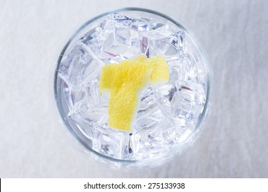 Top View Of A Gin Tonic Balloon Glass With Lemon Peels On It On A Flavoring Process On A Gin Tonic Preparation Session - Focus On The Lemon Peel