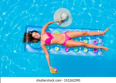 Top View Of A  Girl With Cocktail On A Lilo In The Swimming Pool