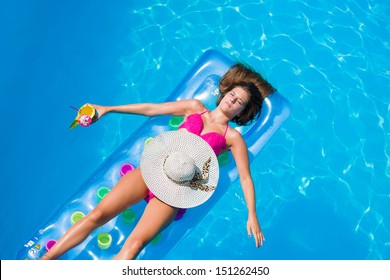 Top View Of A  Girl With Cocktail On A Lilo In The Swimming Pool