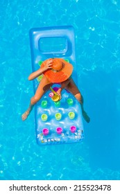 Top View Of A  Girl In The Swimming Pool Relaxing On A Lilo