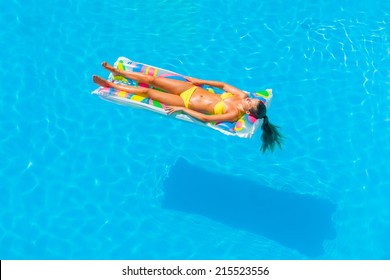 Top View Of A  Girl In The Swimming Pool Relaxing On A Lilo