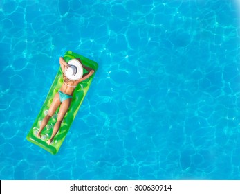 Top View Of A  Girl In The Swimming Pool On A Lilo