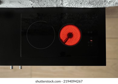 Top View Of Glass Ceramic Cooker Top With Heat Burner On Black Worktop Surface. Modern Stove At Kitchen Room In Loft Style Apartment. Concepts Of Built In Appliance