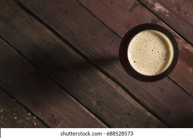 Top View Of A Glass Of Cold Dark Beer Placed On A Rustic Wooden Table