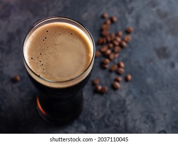 Top view of a glass of dark stout or porter beer with coffee added. Dark background