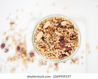 Top view of glass jar filled with fresh granola with nuts and dried fruits placed on white table - Powered by Shutterstock