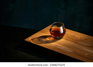 Top view of glass of whiskey, rum, brandy or bourbon standing on wooden table over dark background. Concept of alcohol, strong spirits, drinks, liquid, nightlife, restaurant, club, pub. Ad