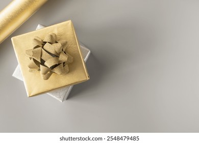 Top view, gold gift box with golden bow on grey background and gift wrapping paper. Concept for happy birthday, thank you, congratulations, anniversary, Valentine's day. - Powered by Shutterstock