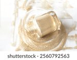 Top view of Gold shimmering nail polish bottle with nail lacquer splashes on white isolated background, beauty and make up ads