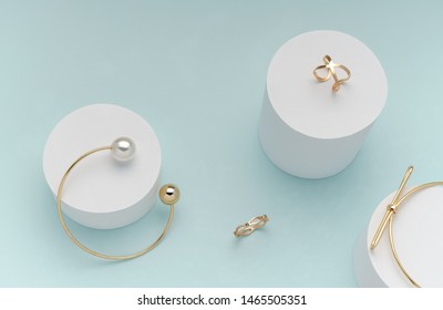 Top view golden bracelets   rings on white cylinders bright pastel color background