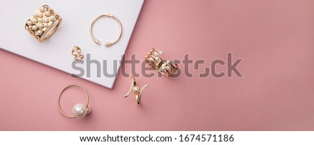 Top view of golden and pearl bracelets on pink and white background with copy space