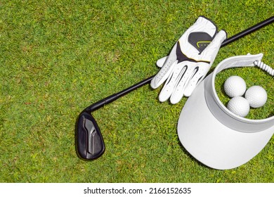 Top View Of Golf Equipment On Green Grass On A Golf Course. Flat Lay Of Golf Club, Balls, Glove And Cap