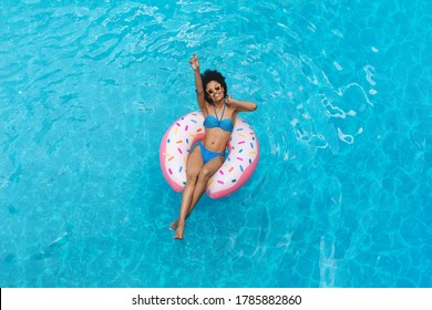 Top view of gorgeous black woman swimming on inflatable ring in pool