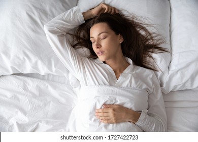 Top view gorgeous woman in white nightwear is in state of deep sleep, peaceful female lying sleeping relaxing under warm soft duvet asleep in comfortable bed, enjoy healthy rest sweet dreams concept - Powered by Shutterstock