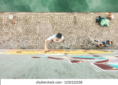 Top View Of Graffiti Artist Painting With Color Spray On The Wall - Urban, Street Art, Millennials Generation, Mural Concept - Focus On His Head