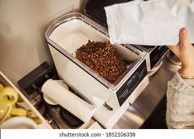 Top View Of A Grain Bin Of The Grinder And Female Barista Putting Necessary Amount Of Coffee Grains Into It