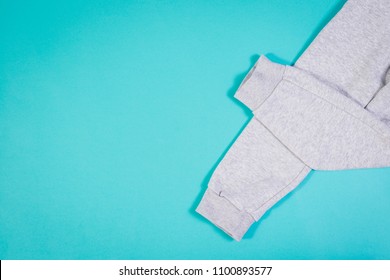 Top view of gray sweatpants on turquoise pastel background. Children's sweatpants with visible two legs.