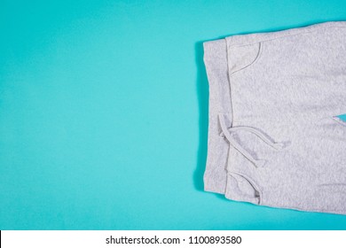 Top view of gray sweatpants on turquoise pastel background. Children's sweatpants with visible two legs.