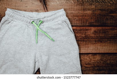 Top view of gray sweatpants on wooden background. Children's sweatpants with visible two legs.