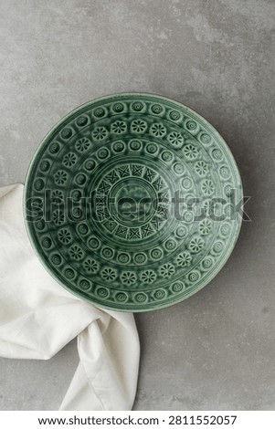 Top view of green ceramic plates on a cement countertop, handmade green ceramic plate on a grey background